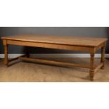 A 19th century rectangular pine kitchen table with turned supports united by a stretcher, 242cm wide