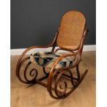 An early 20th century Thonet bentwood rocking chair with caned back and art deco style patterned