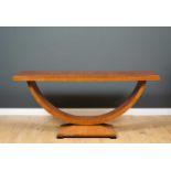 An art deco style walnut side table with arching support and rectangular base with ebonised square
