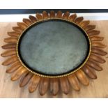 A carved hardwood contemporary sunflower designed circular wall mirror from Sybil Colefax and John