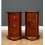 A pair of modern hardwood cylindrical bedside cabinets with three drawers, each with ring handles