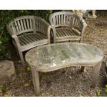 A pair of teak horseshoe shaped garden chairs together with a kidney shaped low table to match,