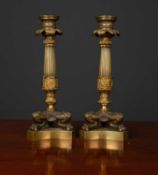 A pair of Regency style gilt metal candlesticks of reeded column form with three paw feet on a