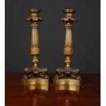 A pair of Regency style gilt metal candlesticks of reeded column form with three paw feet on a