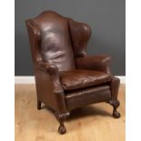 A George III style leather upholstered wing back armchair with arching back, squab cushion and