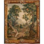 An 18th century Aubusson verdure tapestry with a far reaching mountainous valley view beyond a grove