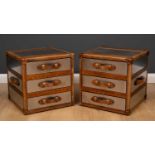 A pair of steel and leather bound packing chest style bedside chests of three drawers with leather