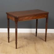 A George III fold over tea table with ring turned tapering legs and decorative inlay to the frieze