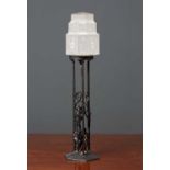 A wrought iron table lamp with oak leaf ornament and stepped art deco style frosted glass shade,