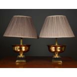 A pair of gilt metal and ebonised table lamps in the form of shallow urns on plinth bases, the table
