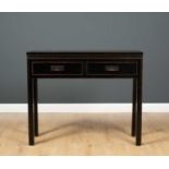 An Oriental black lacquered side table with two drawers and inset handles, 105cm wide x 33.5cm
