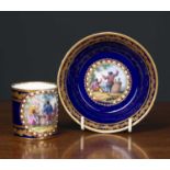 A Sevres porcelain coffee can and saucer on a deep blue ground, with gilt oak leaf banding and