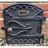 An old cast iron oven door with strapwork style hinges and scrolling ornament, 27cm wide x 42cm