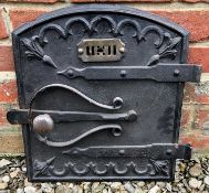 An old cast iron oven door with strapwork style hinges and scrolling ornament, 27cm wide x 42cm