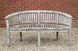 A garden bench with serpentine front and curving backCondition report: In weathered condition and