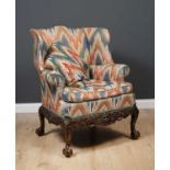 A 19th century George II style mahogany framed wing back upholstered armchair with a carved apron,