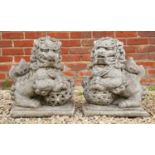 A pair of cast reconstituted stone sculptures in the form of Chinese Dogs of Fo, each with lattice