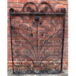 An old black painted wrought iron garden gate decorated with scrolls and a flower, 113cm wide x