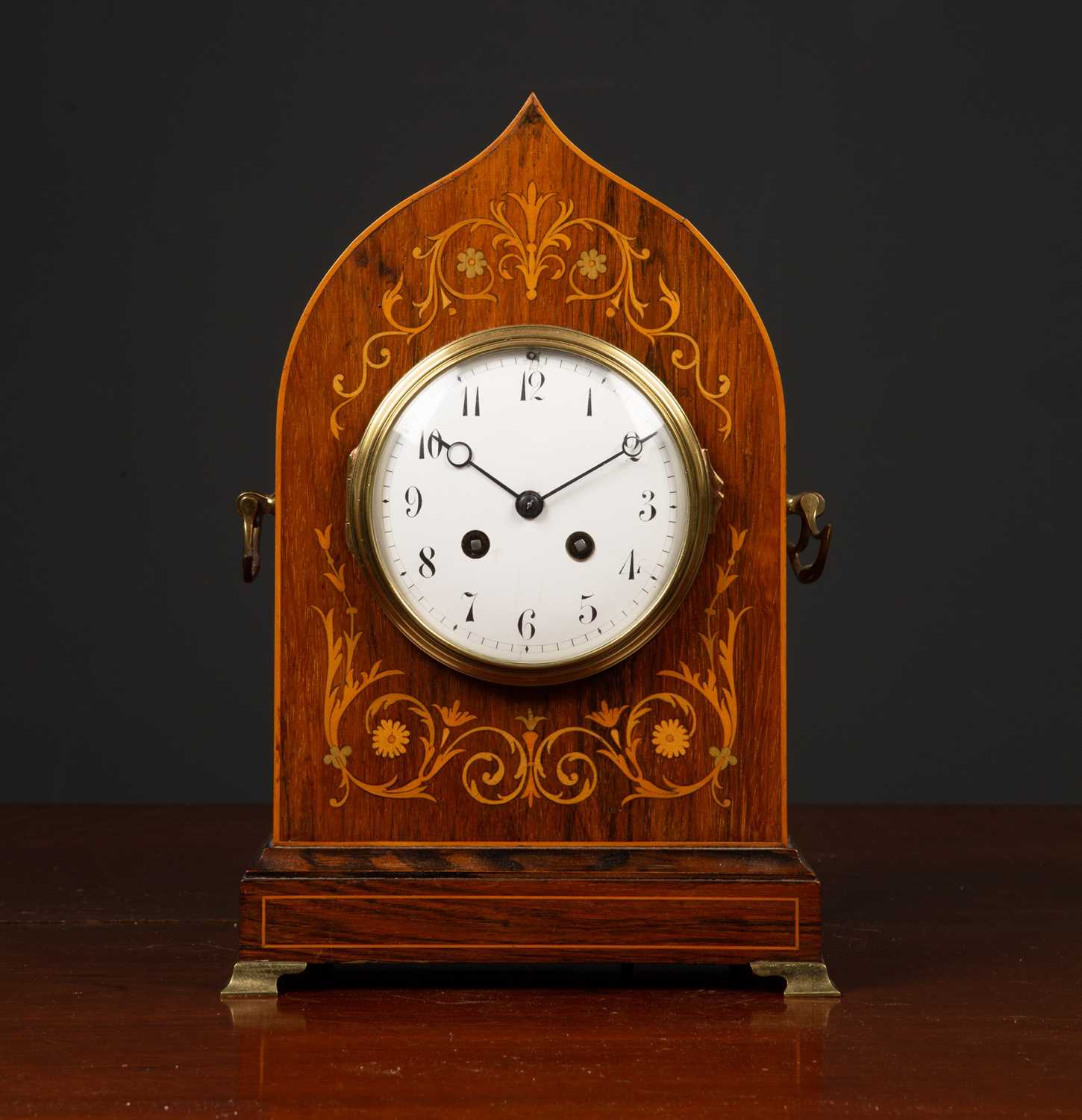 An antique French rosewood cased mantle clock the shaped case with decorative inlay, carrying