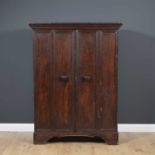 A continental stained pine cupboard with twin panelled doors and on carved bracket feet, opening