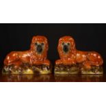 A pair of 19th century Staffordshire pottery lions with glass eyes, each approximately 30cm long x