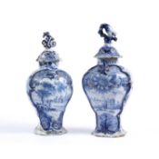 Two late 17th/18th century Delft blue and white pottery vases with covers, each decorated pastoral