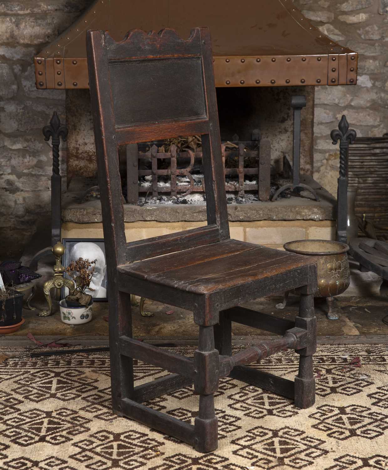 An 18th century oak side chair, the panelled back with shaped top rail, having solid seat, on turned