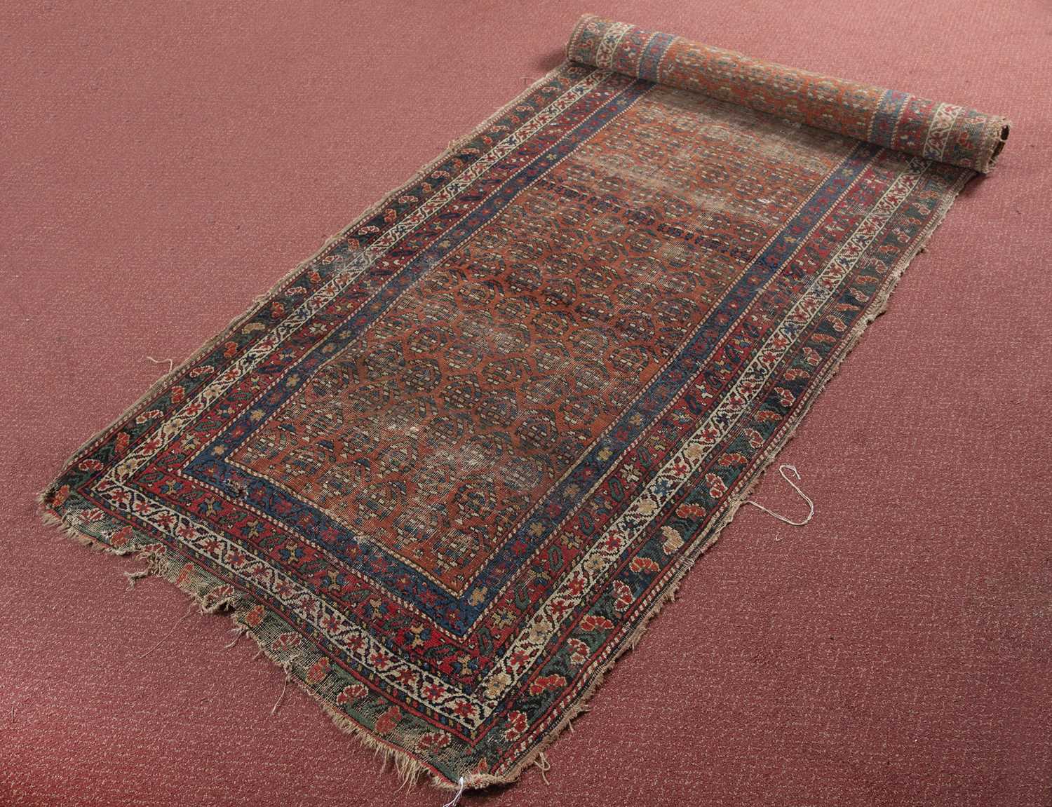 A North West Persian runner with a repeating boteh motif on a red ground with quadruple border,