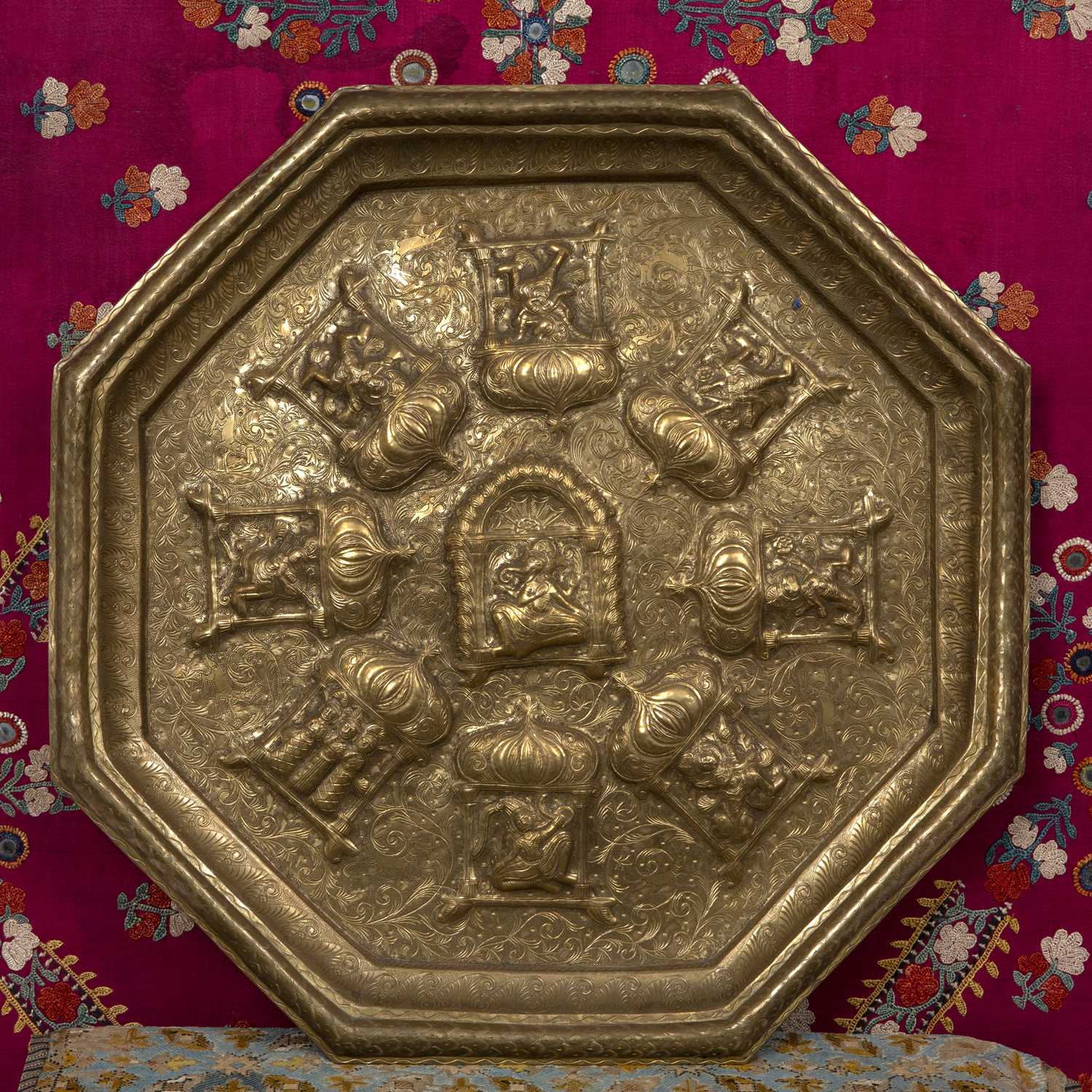 A Northern Indian octagonal brass wall plaque decorated with deities, 49cm wide