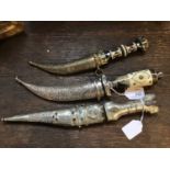 Three Indian daggers, the first with a bone & horn grip and white metal scabbard, another all