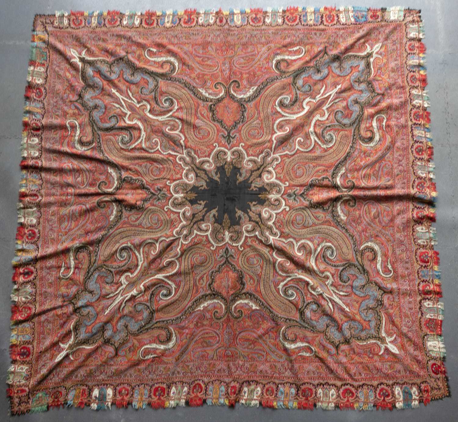 A 19th century Kashmiri shawl, the central black radiating medallion in a red field of scrolls
