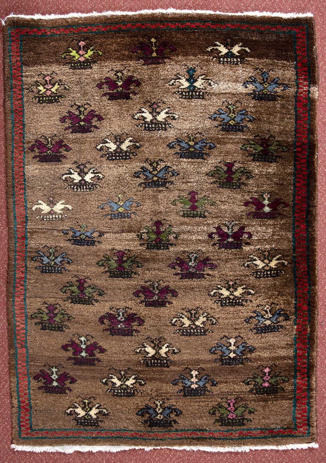 A Turkish rug with multi-coloured flower design on a brown ground, 115 x 81cm