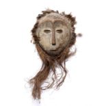 A Lega mask, carved wood, incised circle-dot decoration with a banded feather border and fibre