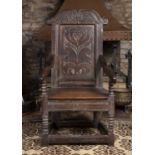 A late 18th century oak wainscot chair, the shaped panelled back carved with a stylised flowerhead