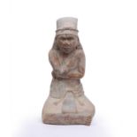 A tall seated clay pottery figure, possibly Peruvian, with crossed arms and legs, white pigment in