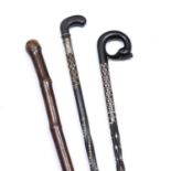 Two old Sri Lankan ebony and ivory inlaid walking sticks and a bamboo stick with brass mounts,