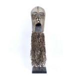 An early 20th century Kifwebe, Songye female mask on stand, with white pigments, raffia beard and