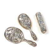Matched three-piece silver dressing table set decorated with cherubs amongst clouds, the mirror
