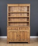 An antique pine dresser with a three tier plate rack above two short drawers and cupboard doors,