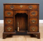 A Georgian style mahogany kneehole desk with seven drawers around a central recess with cupboard and