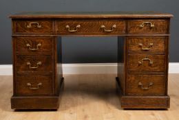 An early 20th century oak and leather inset pedestal desk with nine drawers, 122cm wide x 66cm