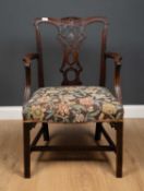 A 19th century carved mahogany open armchair with a pierced splat back, scrolling arms and