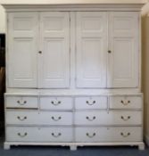A large Irish antique white painted pine cabinet and drawers with four panelled doors above ten