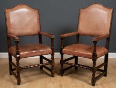 A pair of brown leather upholstered open armchairs with arching backs and turned supports, 60cm wide