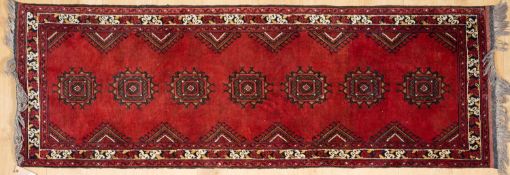 A modern Oriental red ground small runner with seven ornamental motifs to the centre, 84cm long x