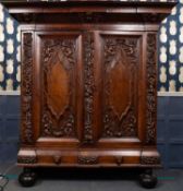 A 17th century style continental walnut cabinet adorned with carved cherubs and fruiting vines,