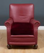 An early 20th century red leather upholstered armchair with turned wooden feet, 80cm wide x 80cm