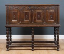 An antique oak side cabinet of panelled construction, turned supports united by stretchers, 126cm