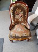 A Victorian mahogany framed low chair with needlework upholstery, cabriole legs and brass casters,