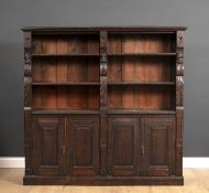 A late 19th century carved oak bookcase with open shelves above panelled doors below, all raised